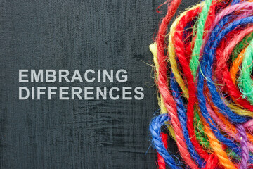 Fototapeta premium Words Embracing differences next to a ball of colored threads.