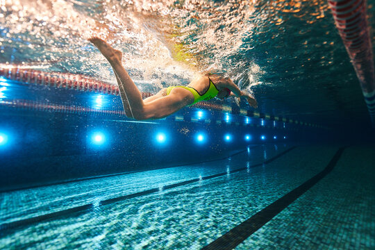 a beautiful young athletic girl in a yellow swimsuit and swimming goggles swims in a sports pool. underwater photography - Powered by Adobe