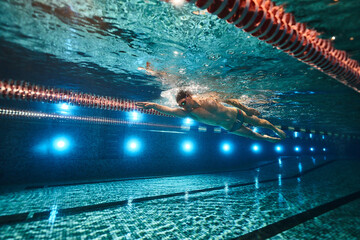 an athletic man swims in the pool. swimmer. underwater photography. freestyle swimming