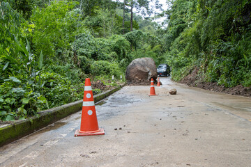 selective focus Orange cones on the road Large boulders fall from the mountain, blocking a rural...