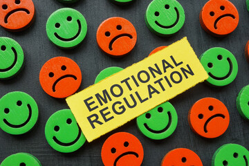 The inscription emotional regulation lies on happy and sad emoticons.