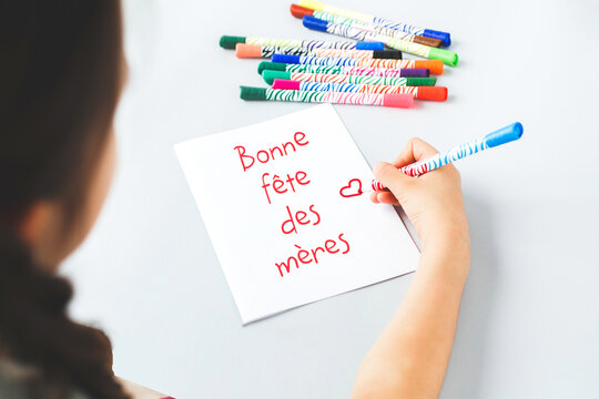 child's hand draws a gift card with felt-tip pens and pencils happy mother's day in French, mother's day holiday concept