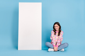 Full length photo of young pretty girl sit floor promoter advertise isolated over blue color background