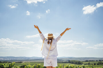 Fototapeta premium White female friends in casual clothes and straw hats look at the landscape
