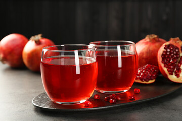 Tasty pomegranate juice in glasses and fresh fruits on grey table