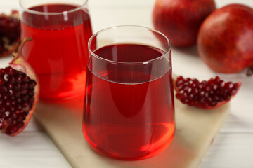 Tasty pomegranate juice in glasses and fresh fruits on white wooden table, closeup