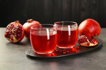 Tasty pomegranate juice in glasses and fresh fruits on grey table