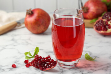 Tasty pomegranate juice in glass and fresh fruits on white marble table