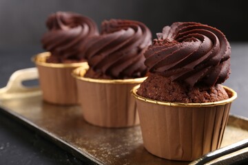 Delicious chocolate cupcakes on black textured table, closeup