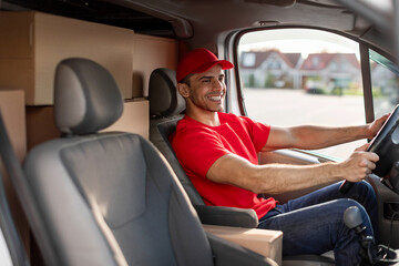 Smiling european courier man sitting in car as driver, delivering parcels to customers