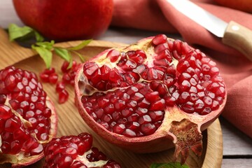 Fresh pomegranates and green leaves on table, closeup