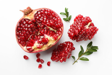 Cut fresh pomegranate and green leaves on white background, flat lay