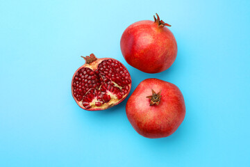 Whole and cut fresh pomegranates on light blue background, flat lay