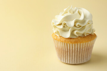 Tasty vanilla cupcake with cream on pale yellow background, closeup. Space for text