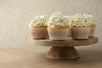 Tasty vanilla cupcakes with cream on wooden table