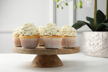 Tasty vanilla cupcakes with cream on white wooden table