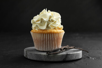 Tasty cupcake with cream and vanilla pods on black table, closeup