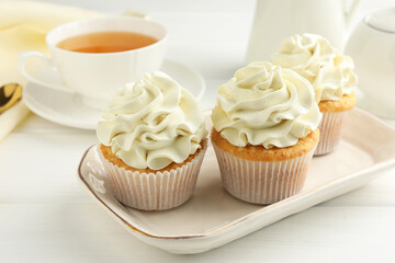 Tasty cupcakes with vanilla cream on white wooden table, closeup