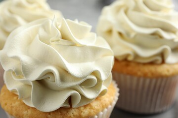 Tasty cupcakes with vanilla cream on table, closeup