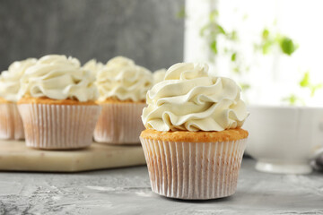 Tasty cupcakes with vanilla cream on grey table, closeup