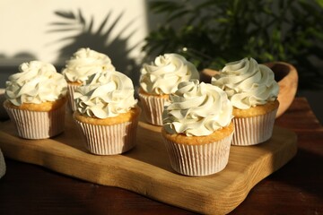 Tasty cupcakes with vanilla cream on wooden table, closeup