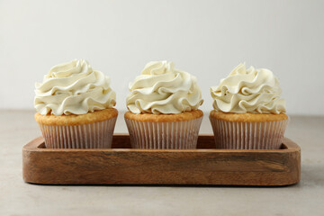 Tasty cupcakes with vanilla cream on light grey table, closeup