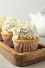 Tasty cupcakes with vanilla cream on light grey table, closeup