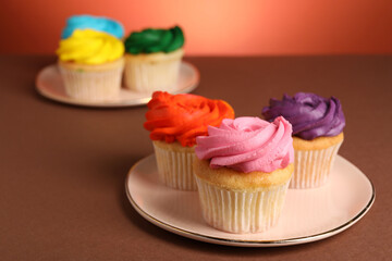 Delicious cupcakes with bright cream on color background