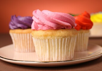 Delicious cupcakes with bright cream on color background, closeup