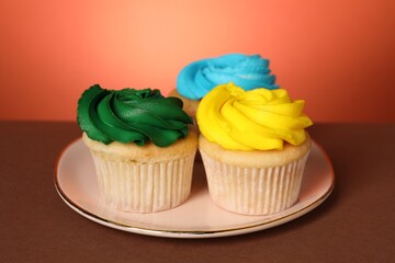 Delicious cupcakes with bright cream on color background