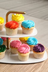 Delicious cupcakes with bright cream on wooden table indoors, closeup