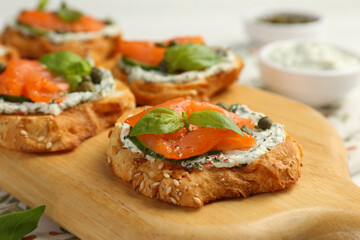 Tasty canapes with salmon, capers, cucumber and sauce on table, closeup