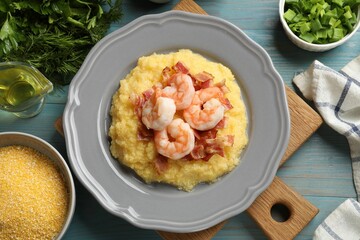 Plate with fresh tasty shrimps, bacon, grits and green onion on light blue wooden table, flat lay
