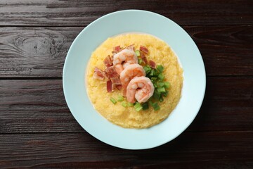 Plate with fresh tasty shrimps, bacon and grits on dark wooden table, top view