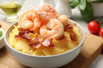 Fresh tasty shrimps, bacon and grits in bowl on table, closeup