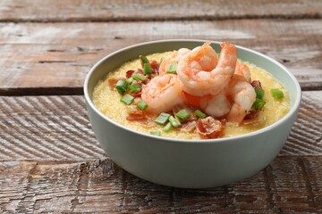 Fresh tasty shrimps, bacon, grits and green onion in bowl on wooden table, closeup