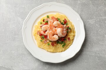 Plate with fresh tasty shrimps, bacon, grits, green onion and pepper on gray textured table, top view