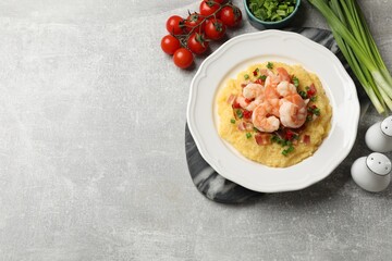 Plate with fresh tasty shrimps, bacon, grits, green onion and pepper on gray textured table, flat...