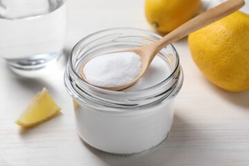 Baking soda, vinegar and lemons on white wooden table, closeup