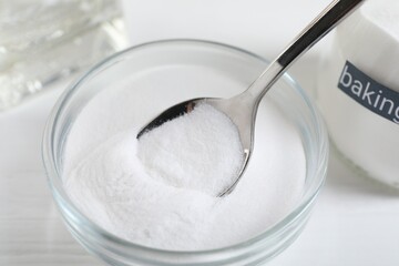Taking baking soda from bowl at white wooden table, closeup