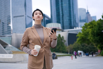 Confident Businesswoman Walking in City with Coffee and Phone