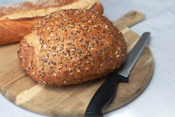Round freshly oat baked bread on a cutting board.