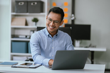 Businessman using laptop computer in office. Happy man, entrepreneur, small business owner working online.