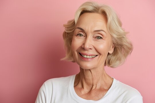 Smiling middle aged woman in 50s in white t shirt on pastel background, wide angle view