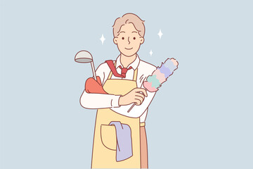 Business man in housewife apron is doing housework and cleaning or cooking after returning from work