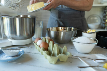 Woman is putting soft butter in a mixing bowl for making batter