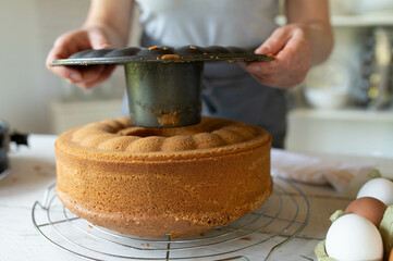 Removing or taking off baking pan from a fresh baked bundt cake by woman´s hands