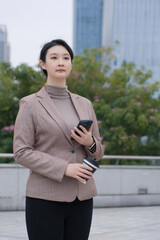 Confident Businesswoman Holding Smartphone and Notebook