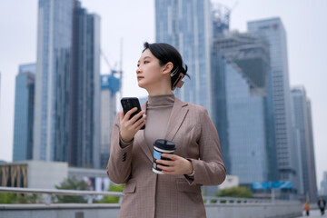Businesswoman with Smartphone and Coffee in Urban Setting