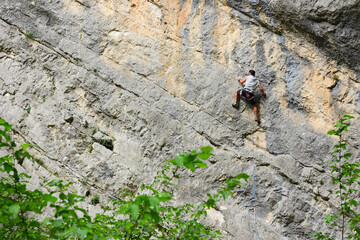 uomo si arrampica su una grande parete rocciosa in montagna, scalata estrema difficile, sport...